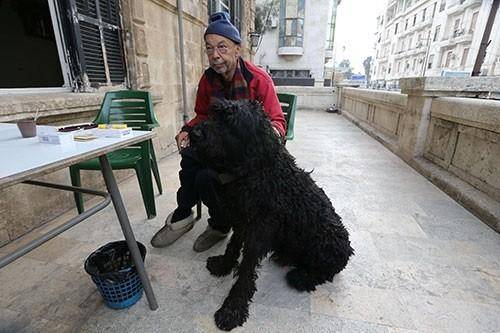 21.11.2014 - Fotoğrafta, çevresindeki çatışmalara aldırış etmeden terasında, köpeği Sasha’yla oturup sigara içen otelin sahibi Armen Mazlumyan görülüyor. Otel, rejim ve muhalifleri ayıran cepheden yalnızca birkaç metre uzaklıkta.